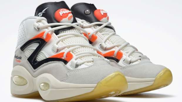 View of white, black, and orange Reebok shoes.